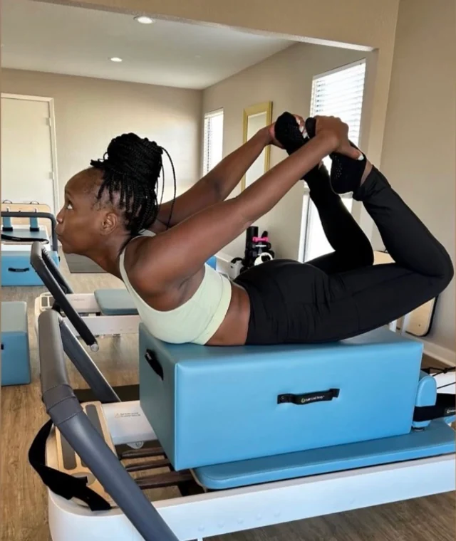 Kayla Hawthorne, founder of Poise and Power, in a bow pose on a Reformer box.
