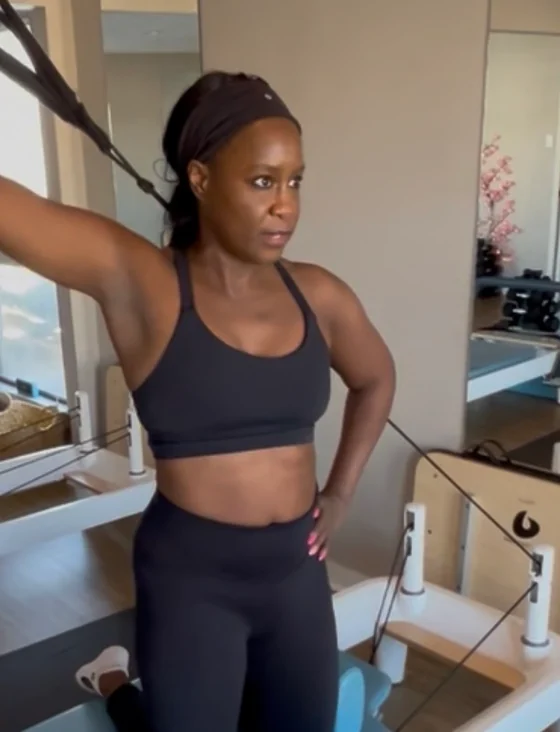 Kayla Hawthorne, founder of Poise and Power, kneeling on a reformer mid-exercise in her studio.